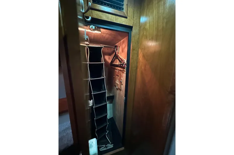 Slide: The Image of Wooden closet interior on 2005 Cruisers Yachts 400 Express, featuring hangers and storage compartments. - 54