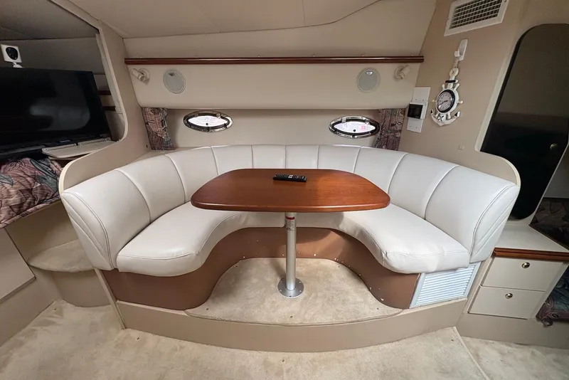 Slide: The Image of Interior of 1999 Cruisers Yachts 3375 Esprit with curved seating and wooden table. - 13