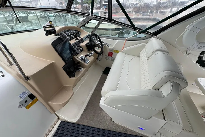 Slide: The Image of 1999 Cruisers Yachts 3375 Esprit helm with white seating and modern controls. - 3