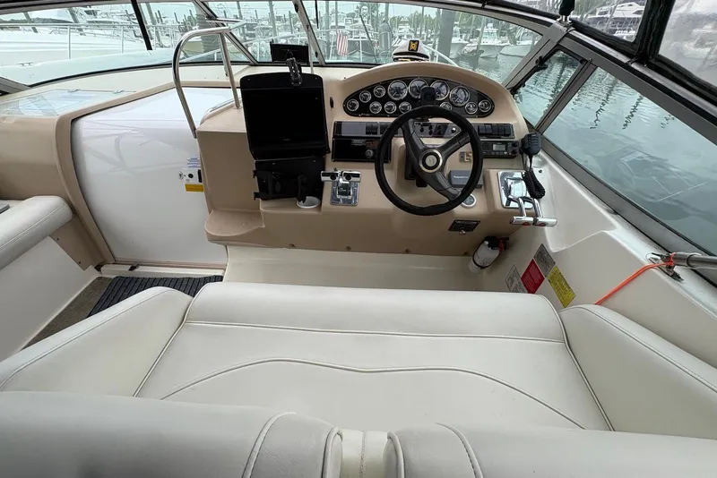 Slide: The Image of 1999 Cruisers Yachts 3375 Esprit helm with steering wheel, gauges, and controls in a marina setting. - 4