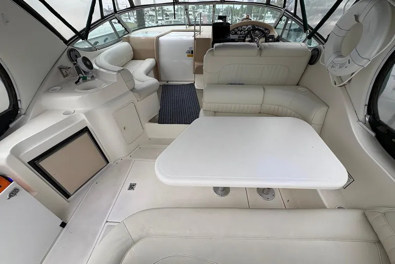 Slide: The Image of 1999 Cruisers Yachts 3375 Esprit interior with white seating and table, showcasing helm and dashboard. - 7