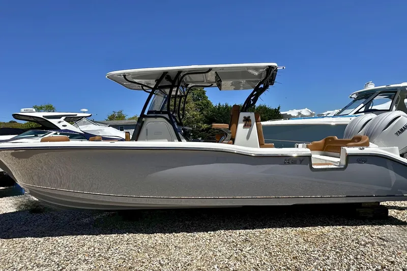 Slide: The Image of 2026 Key West 291 FS boat with sleek design, parked on gravel under clear blue sky. - 1