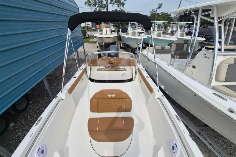 Slide: The Image of 2026 Key West 189 FS boat with tan seating and black canopy in a marina. - 15