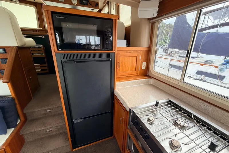 Slide: The Image of Interior of 2002 American Tug 34 featuring kitchen with stove, microwave, and window view. - 11