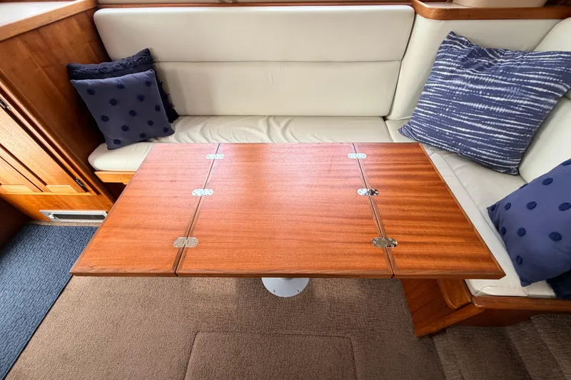 Slide: The Image of Cozy interior of 2002 American Tug 34 with wooden table and cushioned seating. - 18