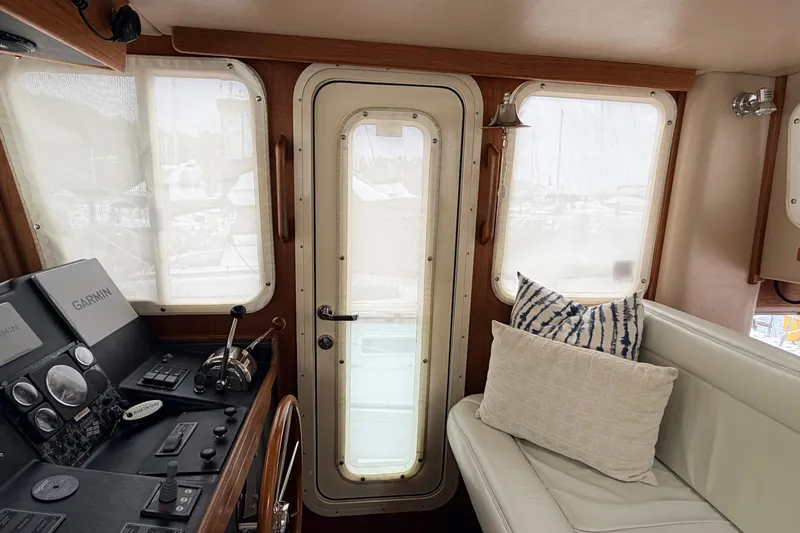 Slide: The Image of Interior of a 2002 American Tug 34, featuring helm controls and cozy seating. - 28