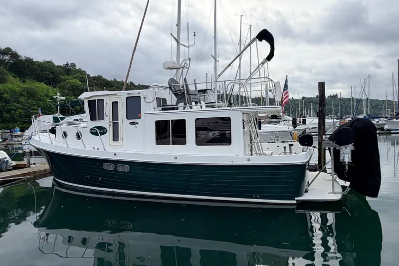 Slide: The Image of 2002 American Tug 34 docked in a marina, surrounded by sailboats. - 3