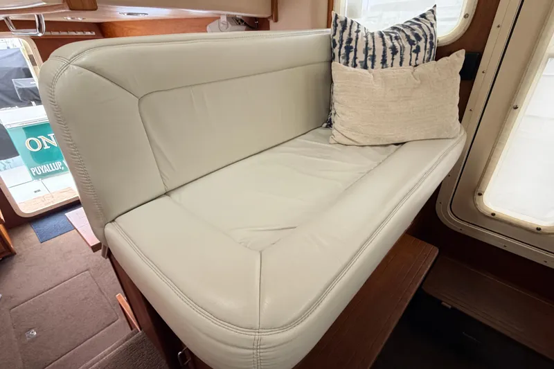 Slide: The Image of Interior of a 2002 American Tug 34 featuring a cushioned seating area with decorative pillows. - 32