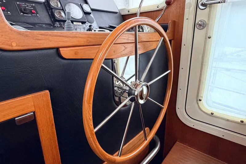 Slide: The Image of Steering wheel of a 2002 American Tug 34 boat, featuring wood and metal design. - 37