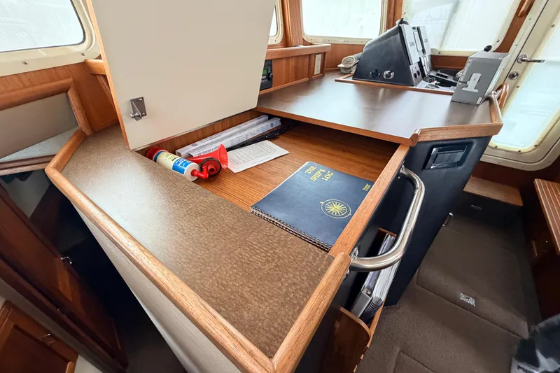 Slide: The Image of Interior of 2002 American Tug 34, featuring navigation desk and ship's logbook. - 39