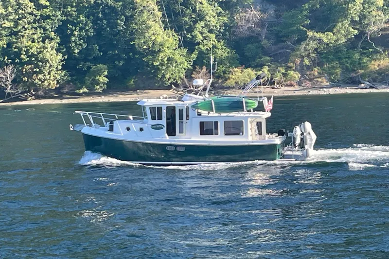 Slide: The Image of American Tug 34, 2002 model, cruising on a scenic river with lush green trees. - 4