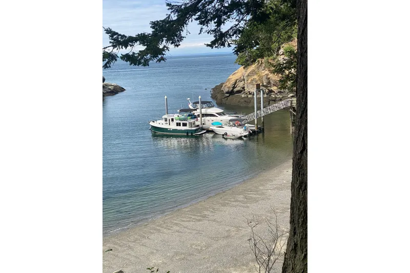 Slide: The Image of Boats docked in a serene cove, featuring a 2002 American Tug 34. - 5