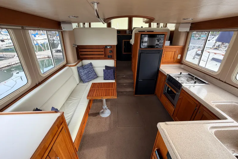 Slide: The Image of Interior of a 2002 American Tug 34, featuring a cozy seating area and modern kitchen amenities. - 6