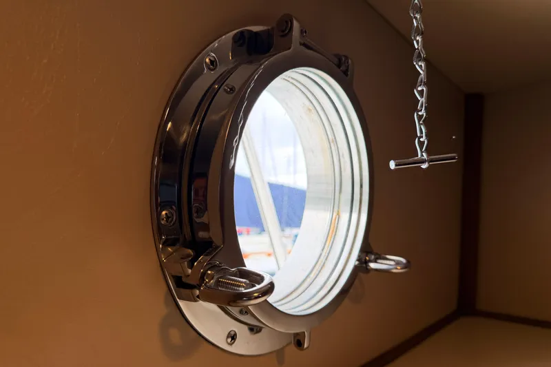 Slide: The Image of Porthole view inside a 2002 American Tug 34 boat, featuring a metal chain handle. - 75
