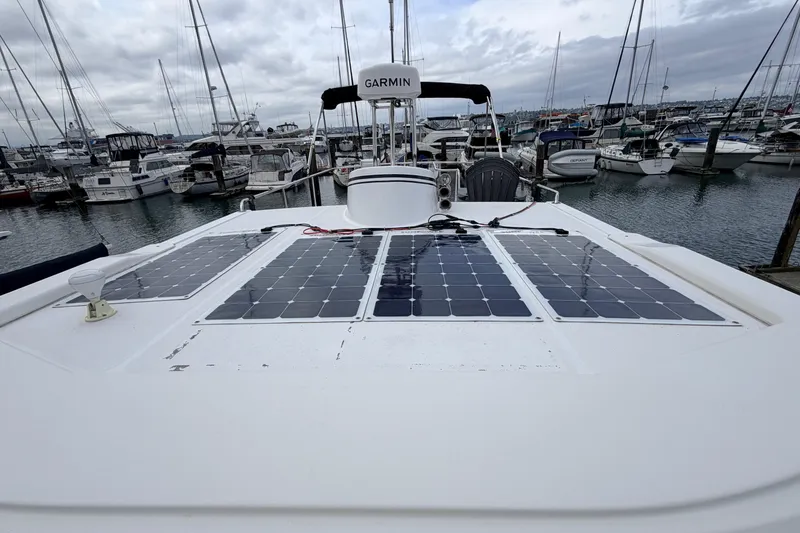 Slide: The Image of American Tug 34 (2002) with solar panels docked at a marina under cloudy skies. - 89