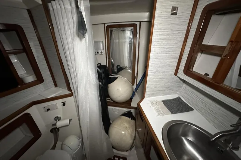 Slide: The Image of Interior of 1991 Catalina 42 sailboat bathroom with sink, toilet, and shower curtain. - 10