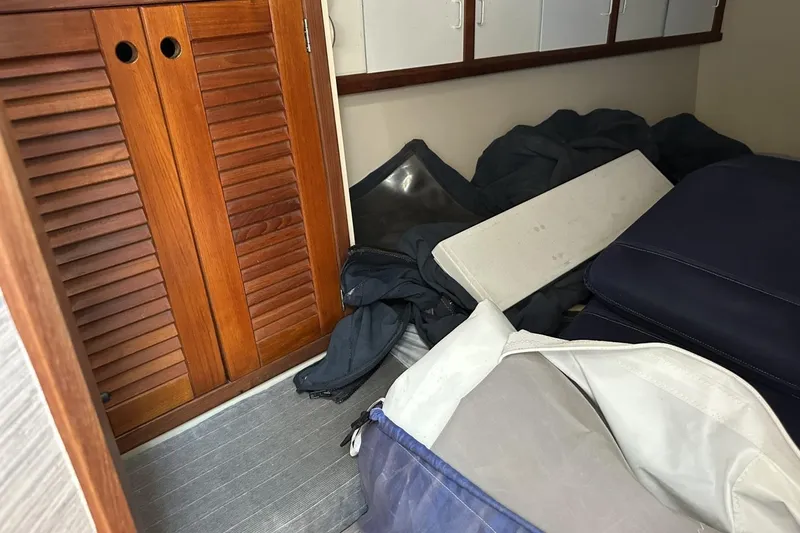 Slide: The Image of Interior of a 1991 Catalina 42 sailboat with wooden cabinets and stored cushions. - 12