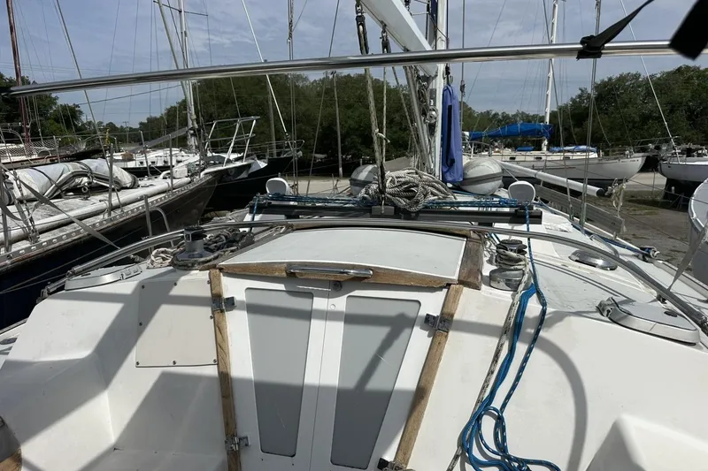 Slide: The Image of 1991 Catalina 42 sailboat cockpit with ropes and winches, docked among other boats. - 128