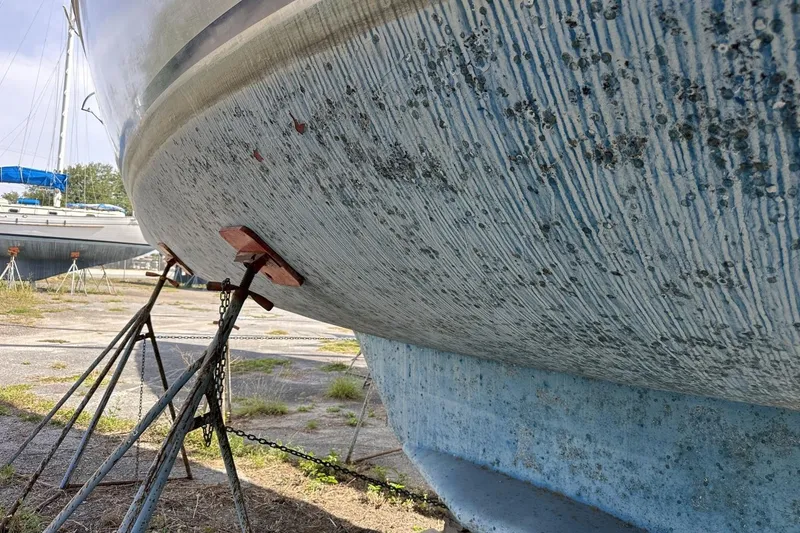 Slide: The Image of 1991 Catalina 42 sailboat hull on stands, showing weathered texture and keel. - 178