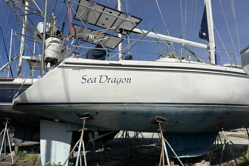 Slide: The Image of 1991 Catalina 42 sailboat "Sea Dragon" on stands, hull visible, in a boatyard. - 190