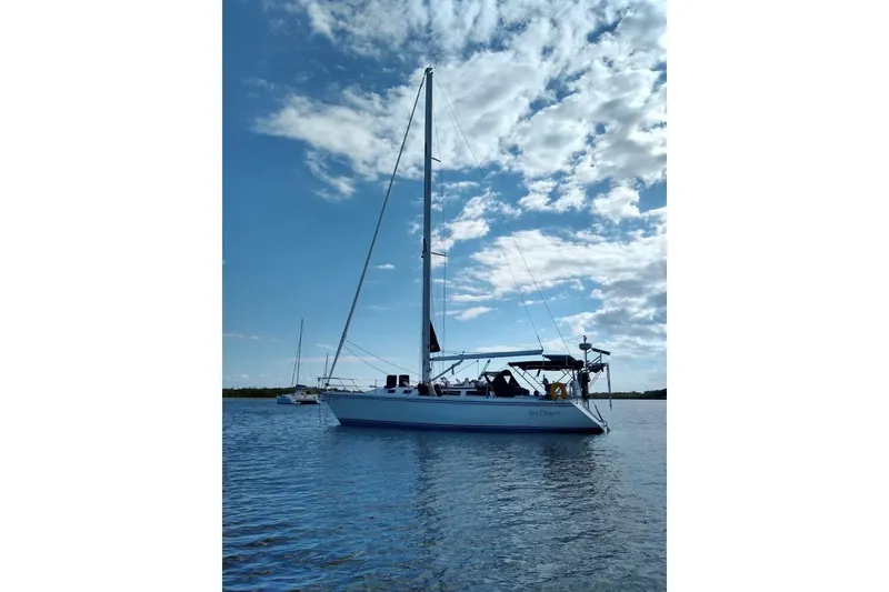 Slide: The Image of Sailboat Catalina 42, 1991 model, anchored on calm water under a partly cloudy sky. - 3