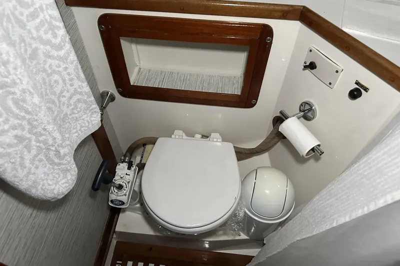 Slide: The Image of Compact bathroom in a 1991 Catalina 42 sailboat, featuring a marine toilet and wooden accents. - 31