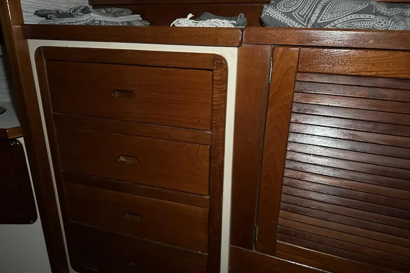 Slide: The Image of Wooden cabinetry inside a 1991 Catalina 42 sailboat, featuring drawers and a louvered door. - 43