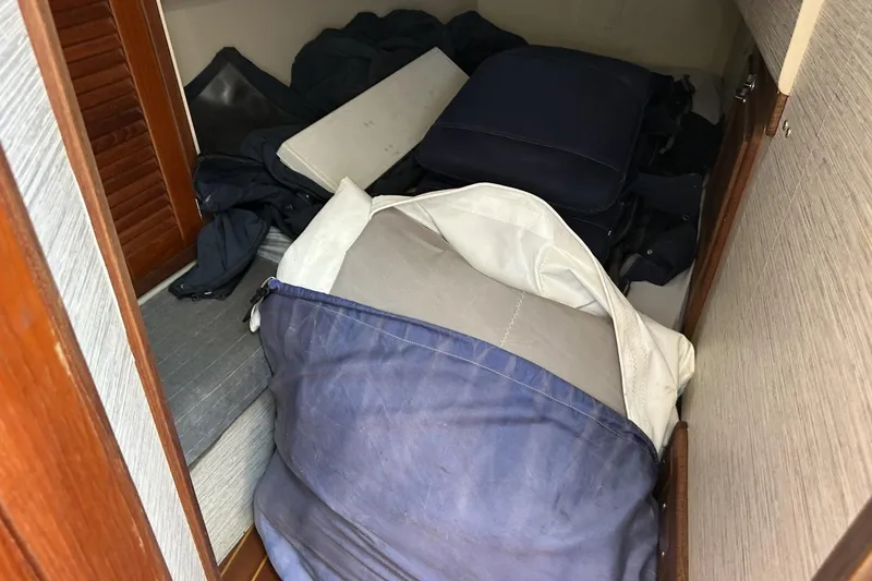 Slide: The Image of Storage area inside a 1991 Catalina 42 sailboat with cushions and bags. - 63