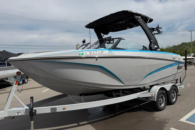 Slide: The Image of 2024 Tigé Z1 boat on trailer, sleek design with blue accents, parked outdoors. - 2