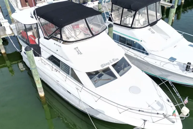 Slide: The Image of 1997 Cruisers Yachts 3650 Motoryacht docked, featuring sleek design and black canopy. - 4