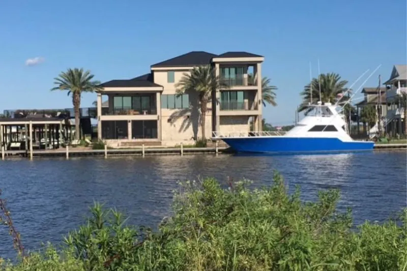 The Image of 1994 Breaux Bay Craft 58 Sportfish yacht docked by waterfront home. - 1