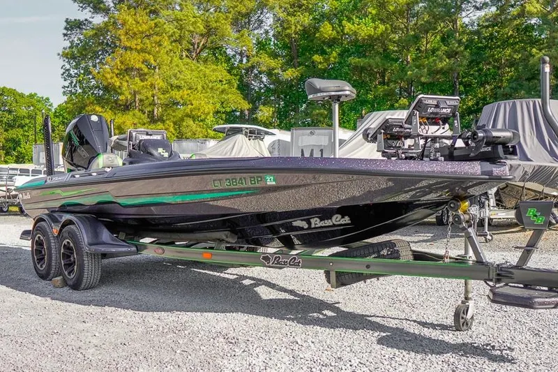 Slide: The Image of 2023 Bass Cat Puma STS boat on trailer, parked outdoors with trees in background. - 2