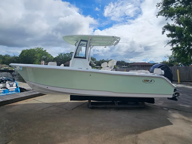 Slide: The Image of 2025 Sea Hunt Ultra 235 SE boat on a dock under a cloudy sky. - 1