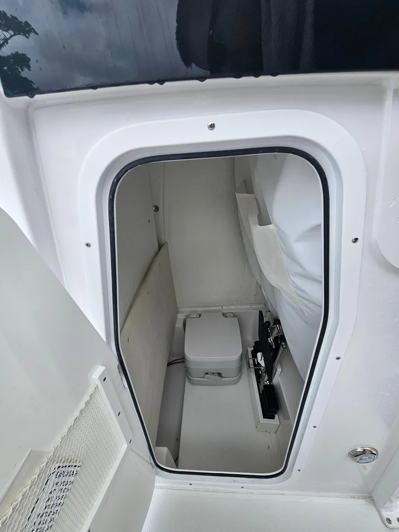 Slide: The Image of 2025 Sea Hunt Ultra 235 SE boat interior with compact marine toilet. - 22
