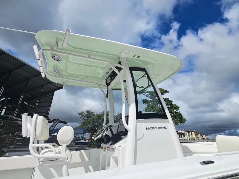 Slide: The Image of 2025 Sea Hunt Ultra 235 SE boat with T-top and seating, under a partly cloudy sky. - 6