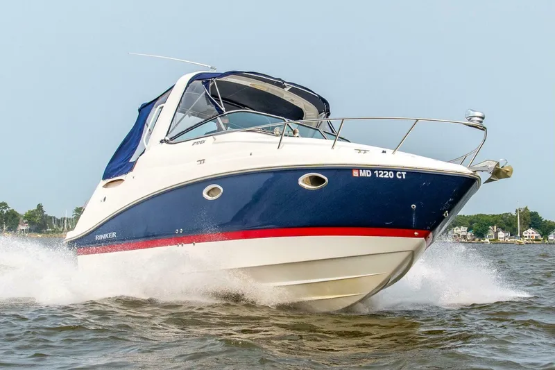 The Image of 2018 Rinker EX 270 boat cruising on water, blue and white design, side view. - 0