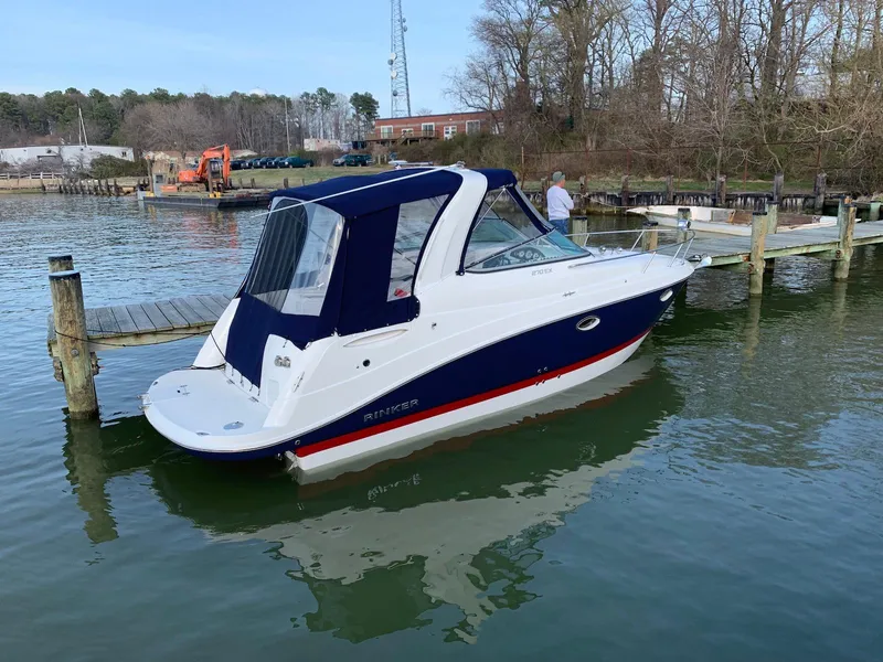 Slide: The Image of 2018 Rinker EX 270 boat docked on calm water with blue canopy. - 15