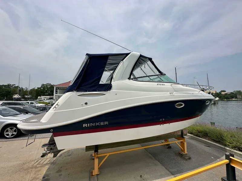 Slide: The Image of 2018 Rinker EX 270 boat on display near waterfront, featuring sleek design and blue canopy. - 23