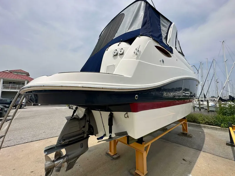 Slide: The Image of 2018 Rinker EX 270 boat on stand, marina background, overcast sky. - 30