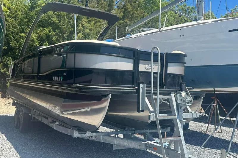 Slide: The Image of 2025 Barletta Lusso 25UCA pontoon boat on trailer, parked outdoors. - 27