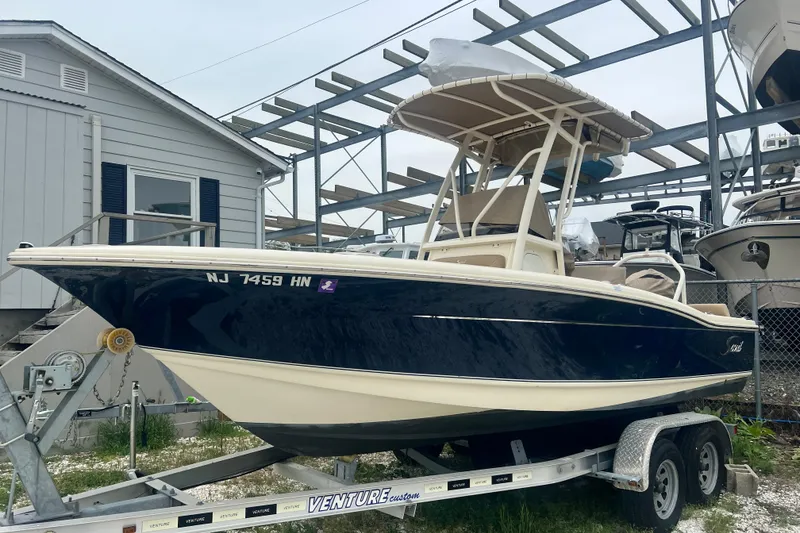 The Image of 2020 Scout 195 Sportfish boat on trailer, parked near a house and other boats. - 0