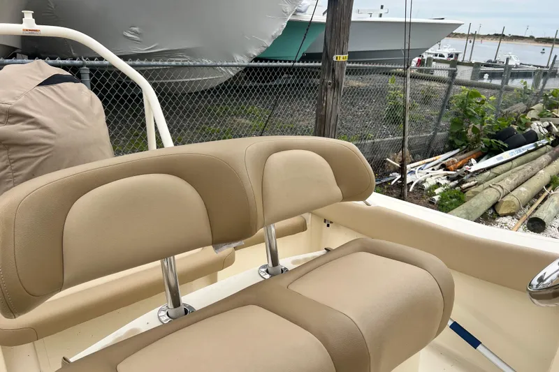 Slide: The Image of 2020 Scout 195 Sportfish boat with beige seating, docked near a fence. - 7
