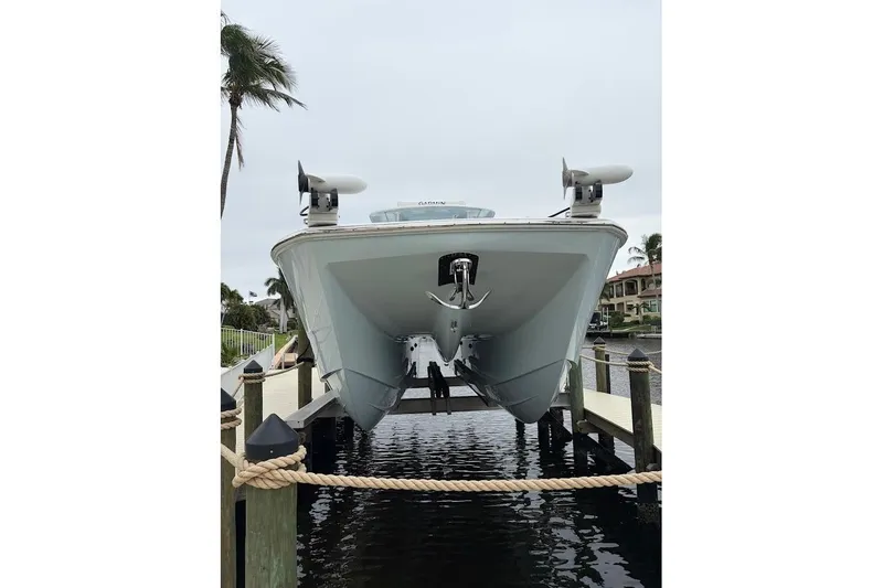 Slide: The Image of 2019 Invincible 40 Catamaran docked, front view with palm trees and waterfront homes. - 5