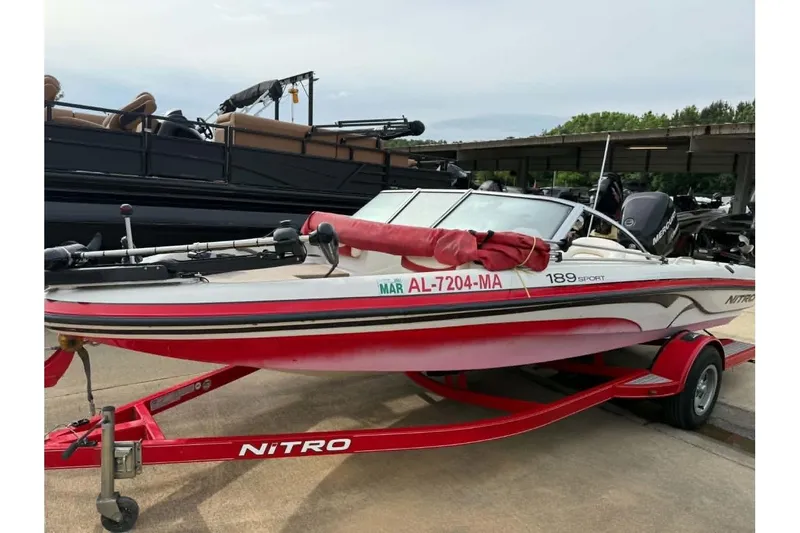 The Image of 2009 Nitro 189 Sport boat on trailer, red and white design, parked outdoors. - 0
