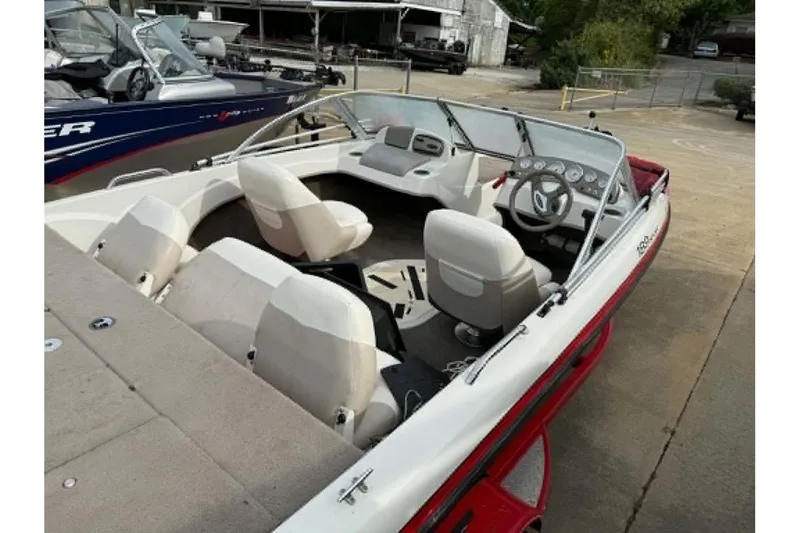 Slide: The Image of 2009 Nitro 189 Sport boat with white interior and steering console, docked outdoors. - 2