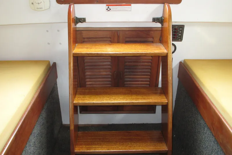 Slide: The Image of Wooden interior steps on a 1979 Roughwater 41 boat, flanked by cushioned seating. - 10