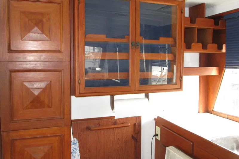 Slide: The Image of Wooden interior cabinetry of a 1979 Roughwater 41 boat, featuring glass doors and shelving. - 17