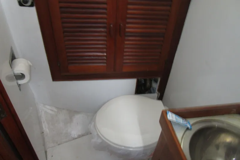 Slide: The Image of Bathroom interior of 1979 Roughwater 41 boat with toilet, sink, and wooden cabinet. - 25
