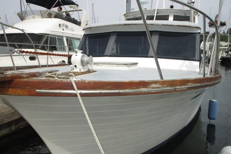Slide: The Image of 1979 Roughwater 41 boat docked, featuring a classic wooden design and white hull. - 43
