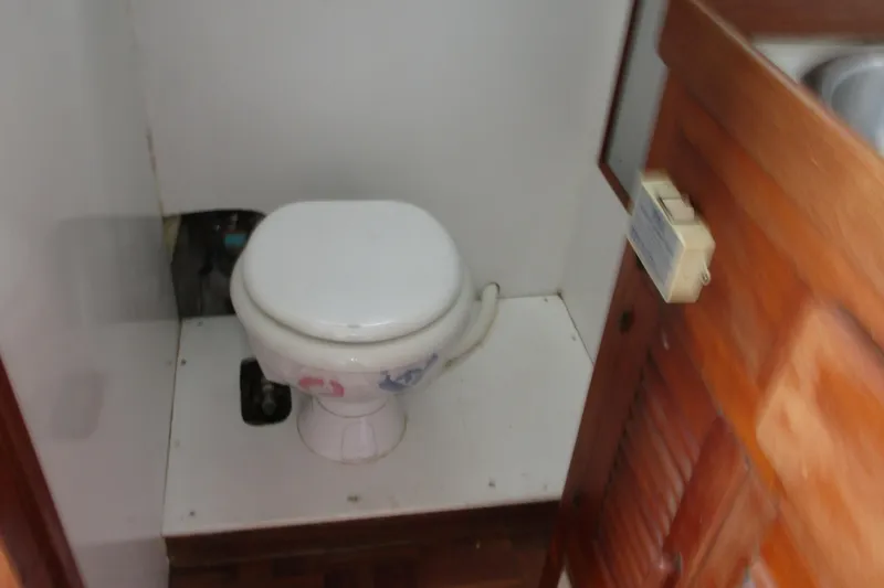 Slide: The Image of 1979 Roughwater 41 boat bathroom with white marine toilet and wooden door. - 7